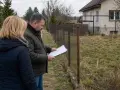Wznowienie granic działki, mężczyzna z dokumentami przy płocie, dyskusja o zasiedzeniu.