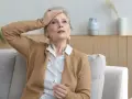 Zmartwiona kobieta z ręką na czole, czuje się przytłoczona naruszeniem prywatności przez sąsiada.