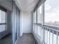 Nowoczesna zabudowa balkonu w bloku, z dużymi oknami i widokiem na miasto. Sprawdź, jaka jest zabudowa balkonu w bloku cena.
