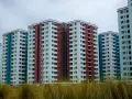 Wielopiętrowe bloki mieszkalne w kolorach białym, czerwonym i niebieskim. Zastanawiasz się, dlaczego deweloperzy nie podają cen?
