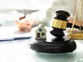 Młotek sędziowski i waga sprawiedliwości obok miniatury domu. Rozważasz, jak podważyć zasiedzenie?