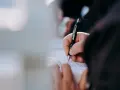 Dłoń pisze długopisem na dokumencie. Kto może zameldować osobę w domu? Właściwa osoba wypełnia formularz.