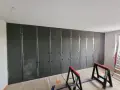 Montaż paneli wygłuszających ścianę od sąsiada. Metalowy stelaż i ciemne płyty tworzą barierę akustyczną.