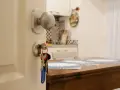 Klucze do mieszkania wiszą przy drzwiach. Czy zakup mieszkania można wrzucić w koszty? W tle kuchnia i stół.