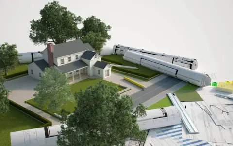 Model domu z planami i materiałami budowlanymi. Część budynku na działce sąsiada, symbolizująca projektowanie i planowanie.