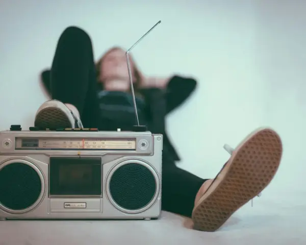 Osoba leży z nogami opartymi o boombox, słuchając muzyki. Idealny sposób, by sprawdzić, jak głośno można słuchać muzyki w dzień.