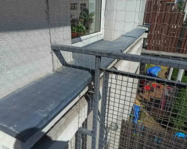 Siatkowanie balkonu cena: siatka zabezpiecza przed wypadnięciem, idealna dla kotów. Widok z góry na siatkę i balustradę.