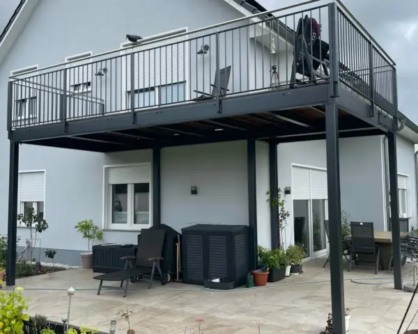 Nowoczesne balkony dostawne na słupach, z czarną balustradą, dodają uroku domowi. Sprawdź, jaka cena za takie rozwiązanie.