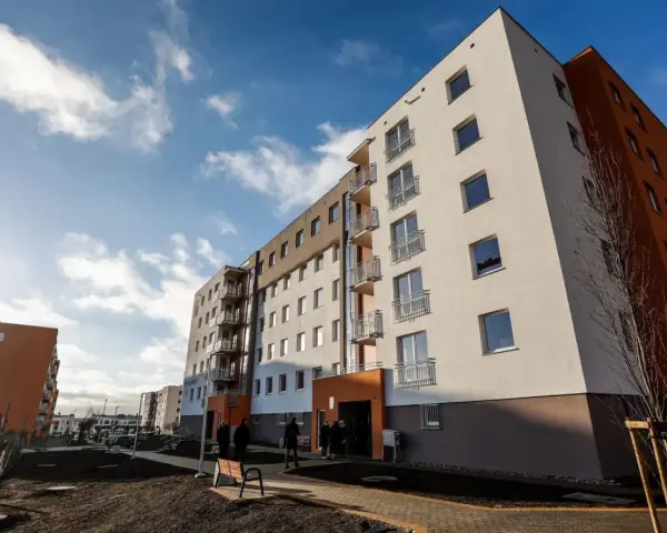 Nowe bloki TBS, idealne na kupno drugiego mieszkania. Jasne fasady, balkony i błękitne niebo.