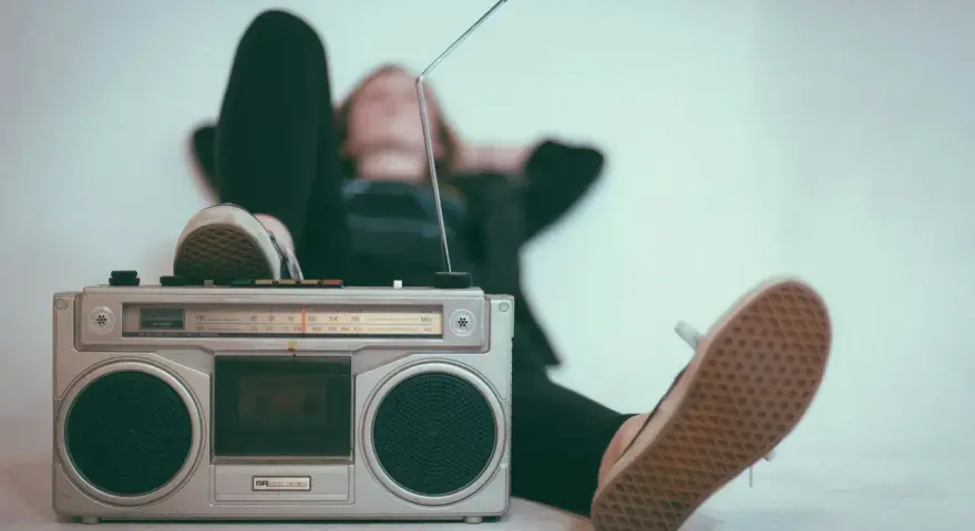 Osoba leży z nogami opartymi o boombox, słuchając muzyki. Idealny sposób, by sprawdzić, jak głośno można słuchać muzyki w dzień.
