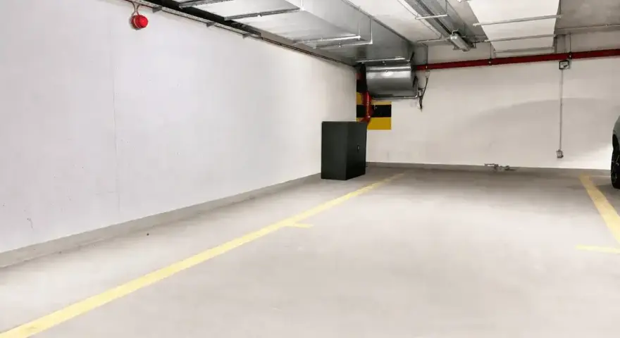 Puste miejsce parkingowe z żółtymi liniami. Idealne do wynajem miejsca parkingowego dla Twojego samochodu.