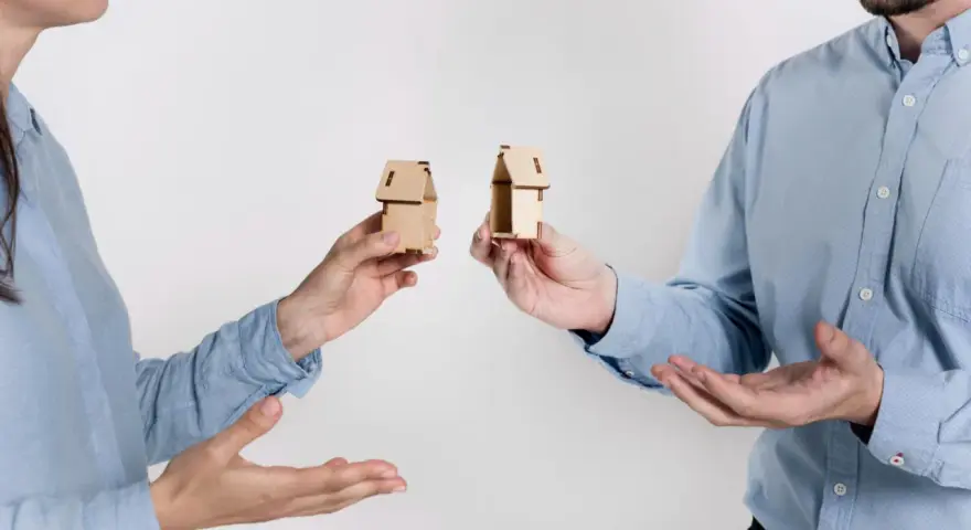 Dwie osoby trzymają miniaturowe domki, symbolizujące zniesienie współwłasności gdy współwłaściciel nie żyje.