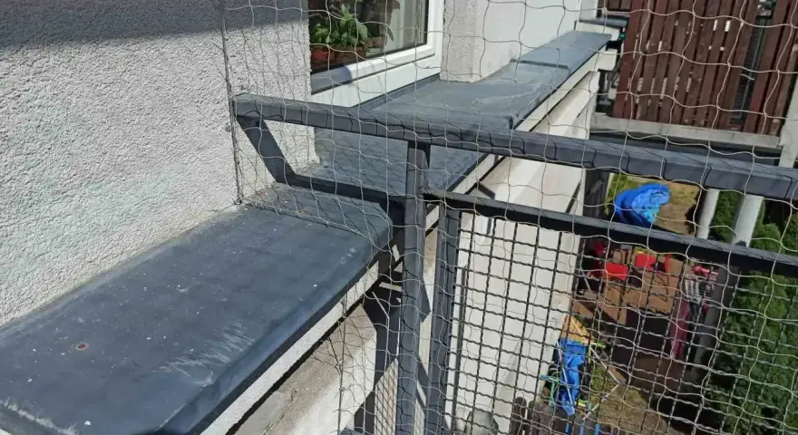 Siatkowanie balkonu cena: siatka zabezpiecza przed wypadnięciem, idealna dla kotów. Widok z góry na siatkę i balustradę.