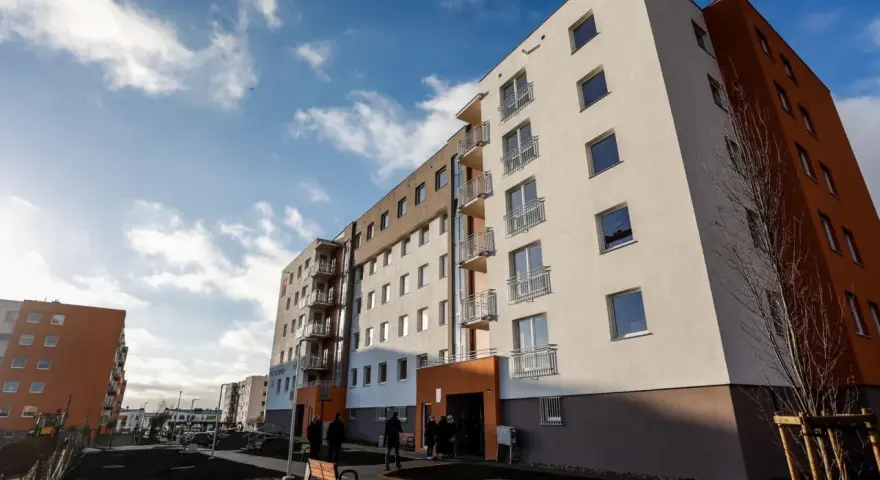 Nowe bloki TBS, idealne na kupno drugiego mieszkania. Jasne fasady, balkony i błękitne niebo.