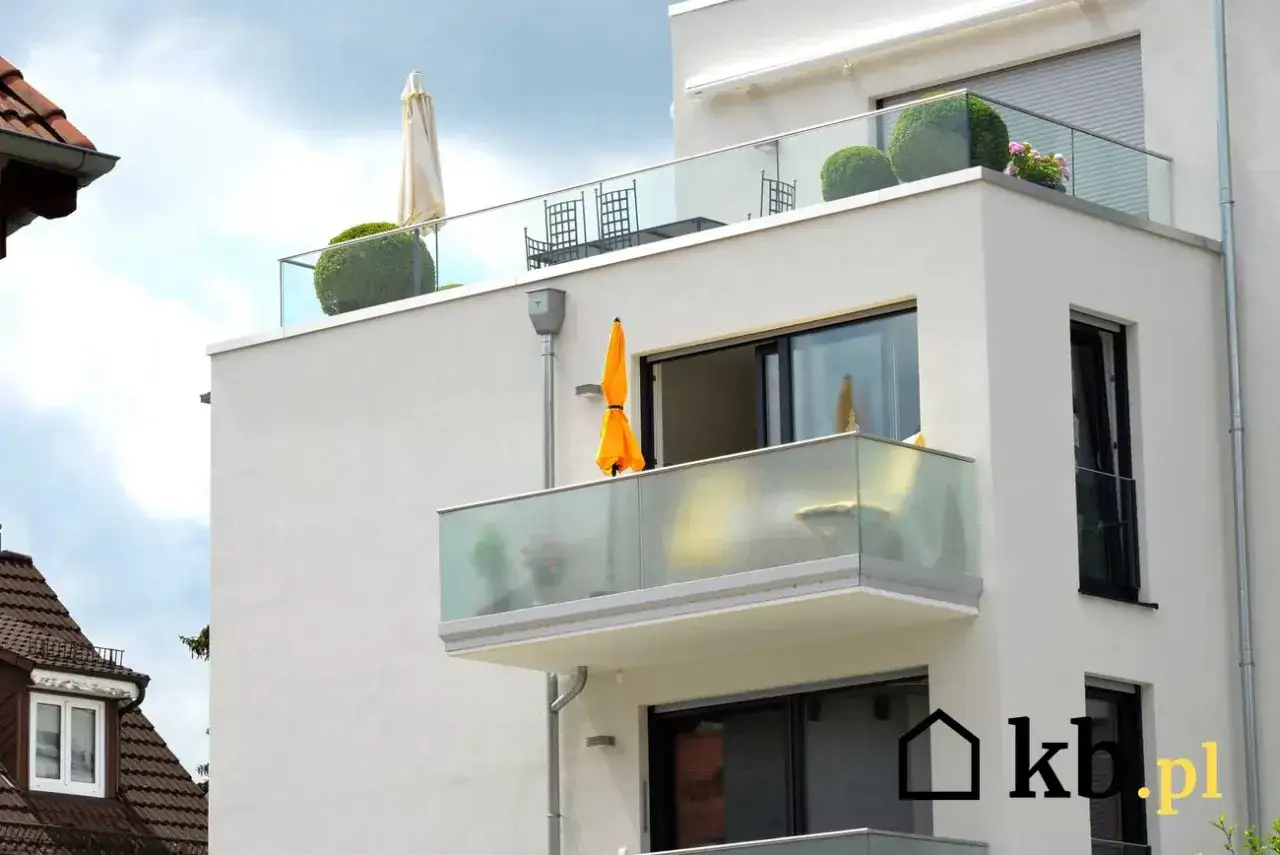Nowoczesny balkon z oszklonymi balustradami i parasolami. Idealne rozwiązanie, czym osłonić balkon przed słońcem i spojrzeniami.