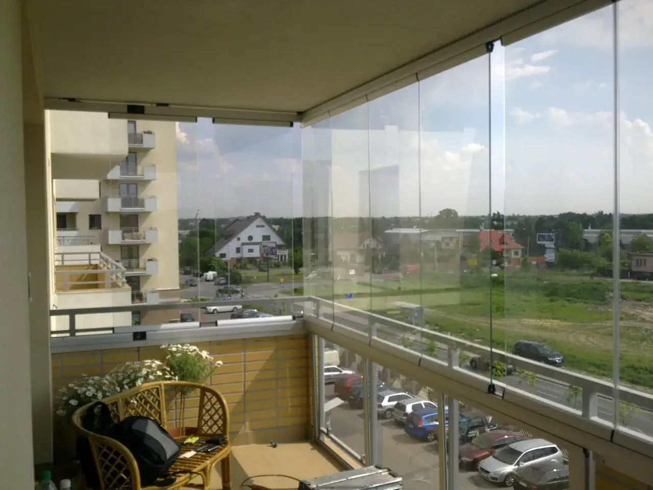 Zabudowa balkonu w bloku cena: szklane panele tworzą przytulne miejsce z widokiem na miasto.
