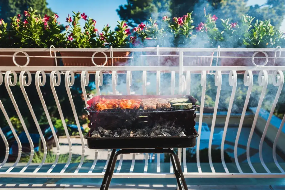 Grill węglowy na balkonie bloku mieszkalnego z dymem