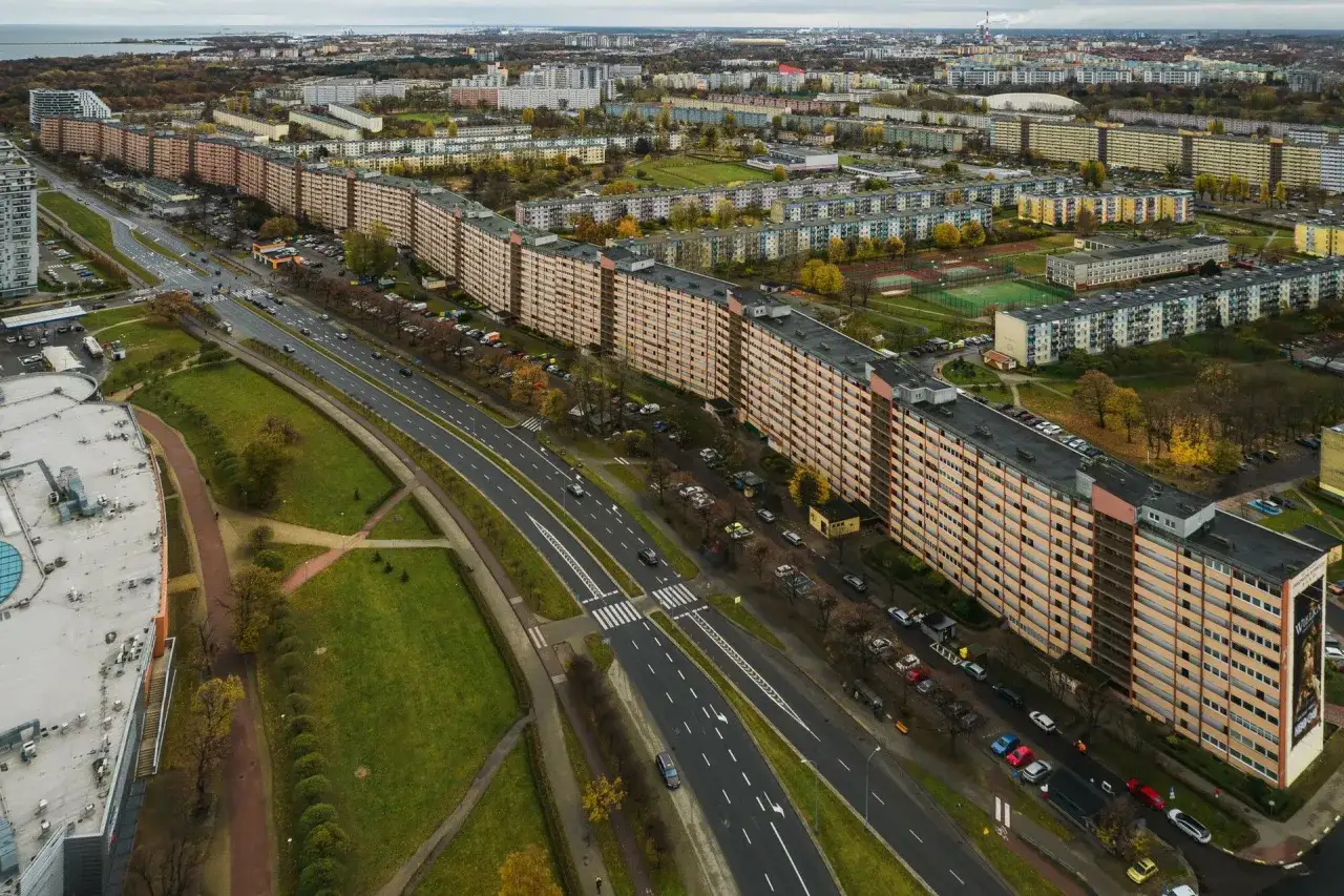 Widok z lotu ptaka na najdłuższy blok w Polsce, ciągnący się wzdłuż drogi z samochodami i zielenią.