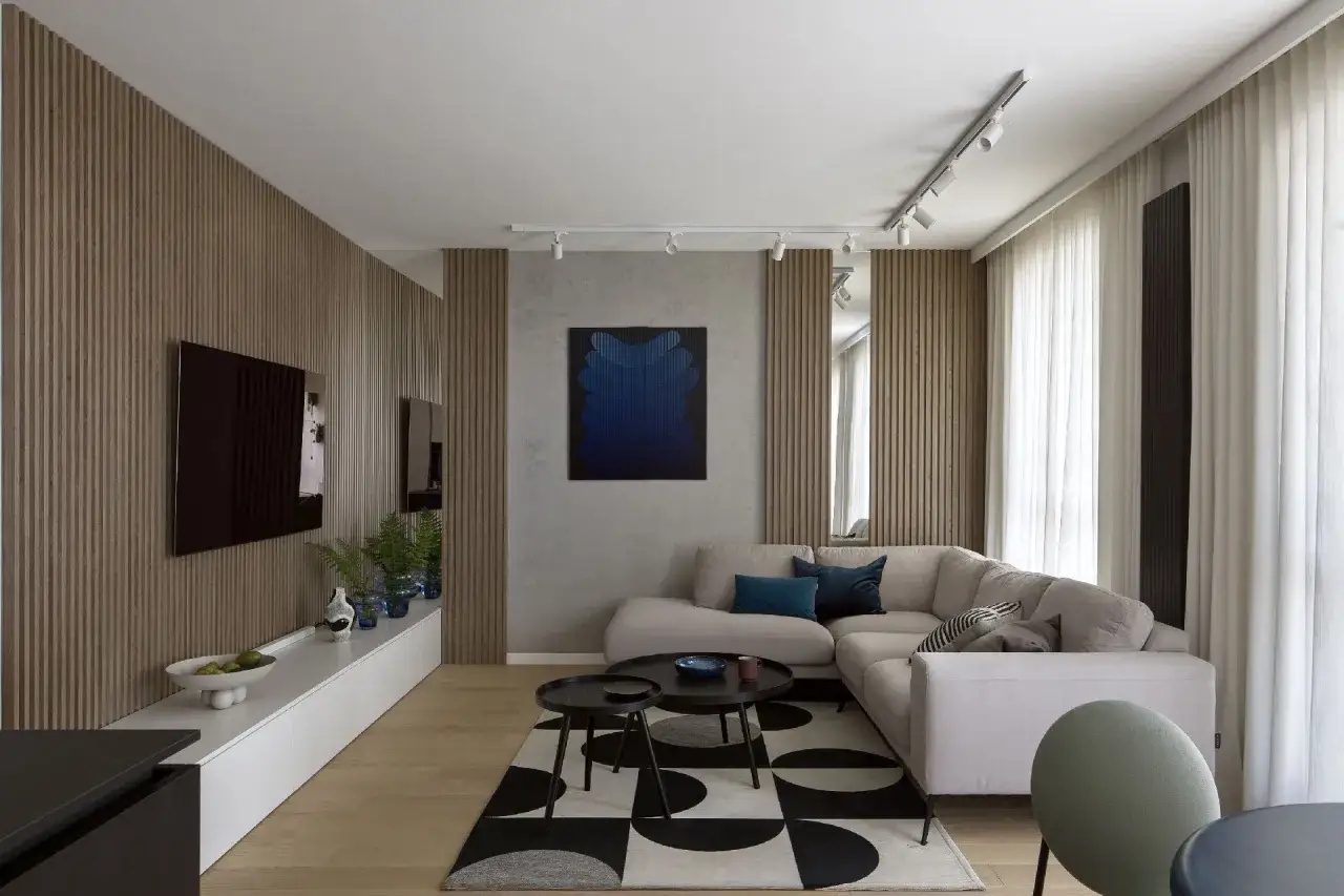 Modny salon w bloku z panelami ściennymi, wygodną kanapą i geometrycznym dywanem.