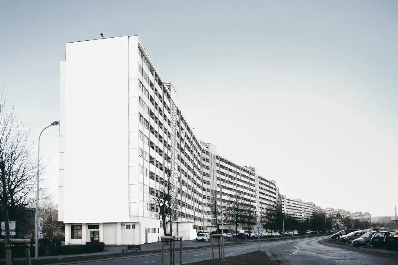 Długi, biały budynek mieszkalny, prawdopodobnie największy blok w Polsce, ciągnie się wzdłuż ulicy.